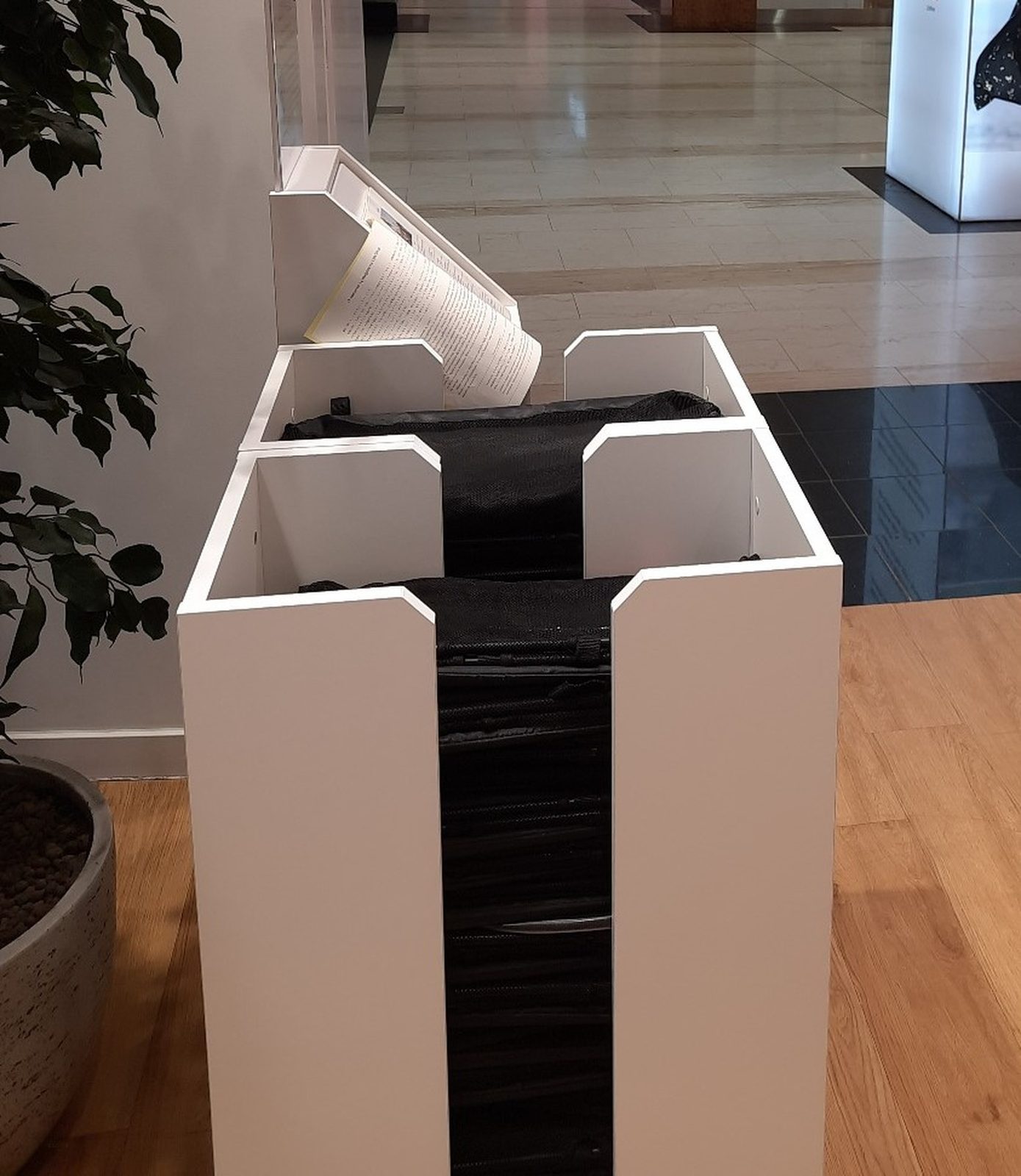 A white box dispenser with black shopping bags