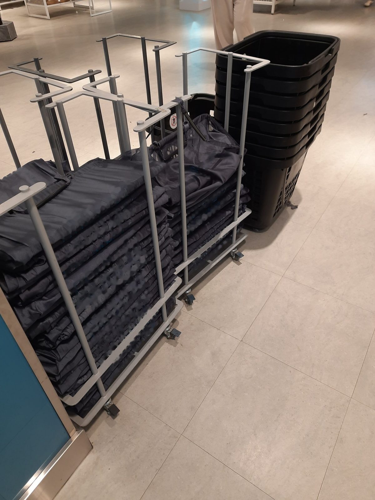 Racks of folded shopping bags and a stack of black baskets