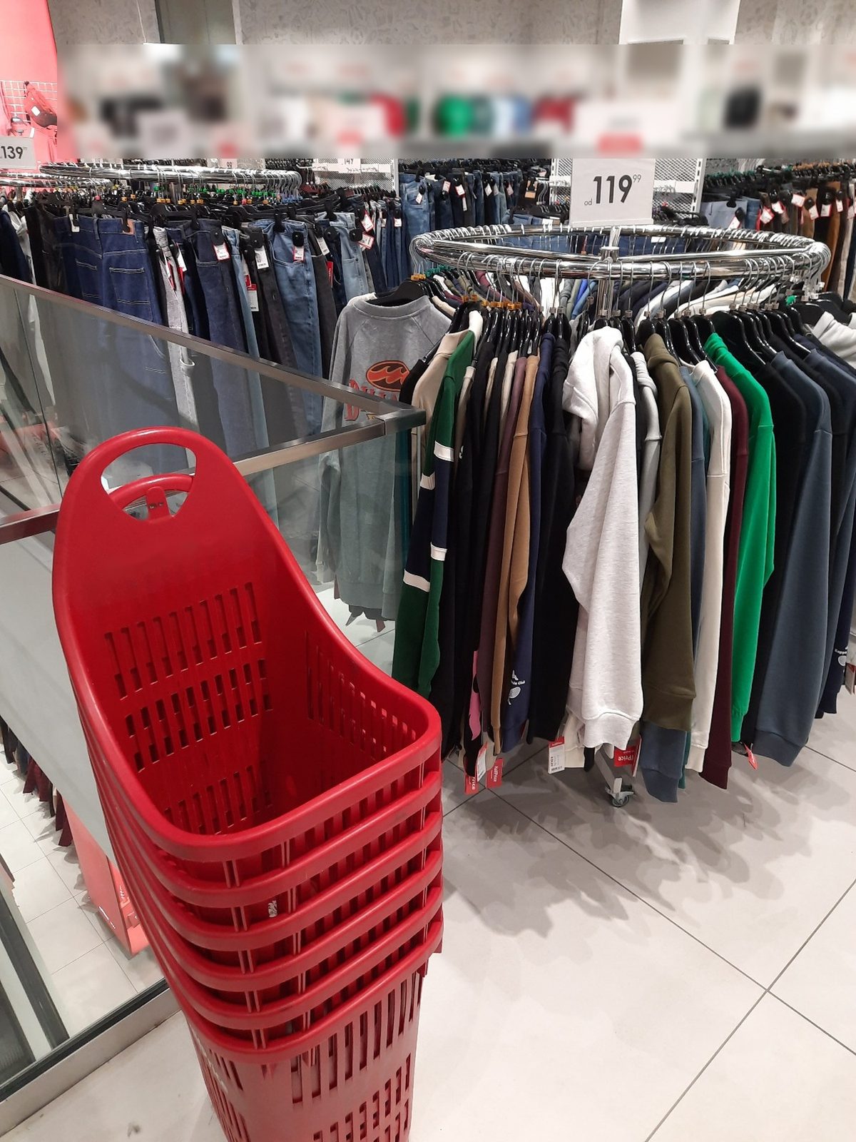 A stack of red plastic wheeled baskets in a clothing store