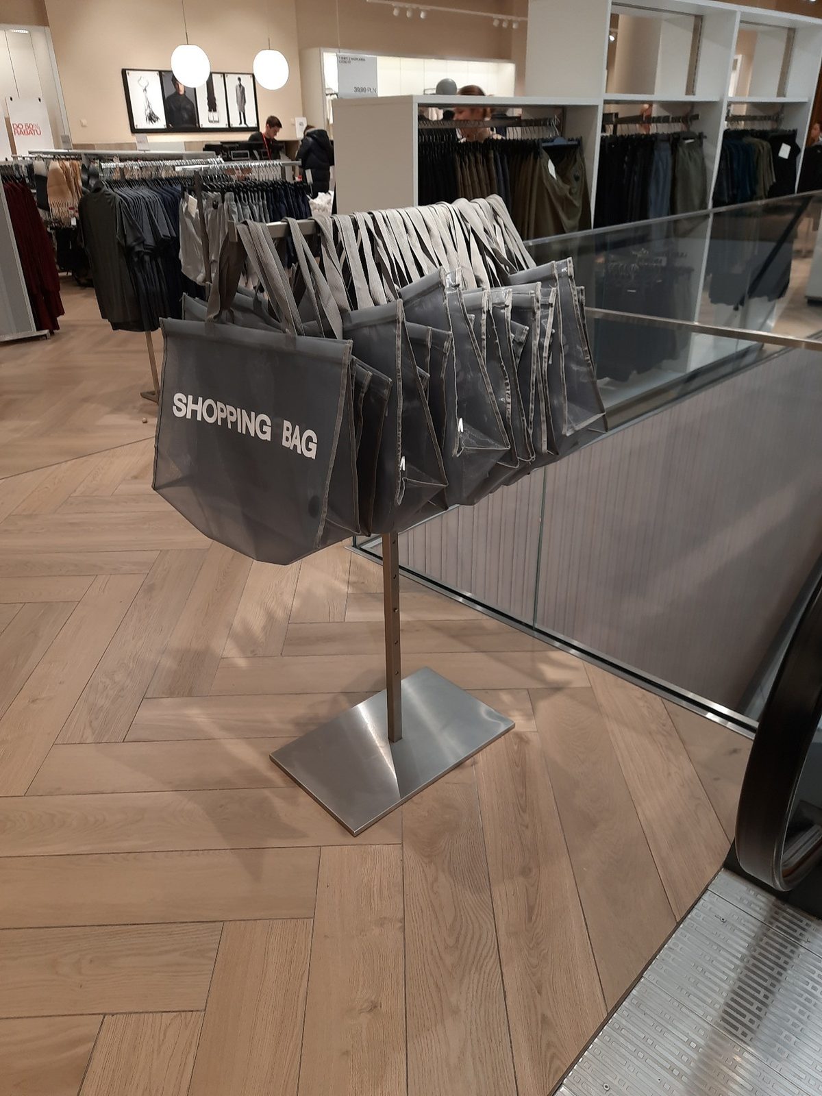 Grey mesh shopping bags hanging on a metal stand