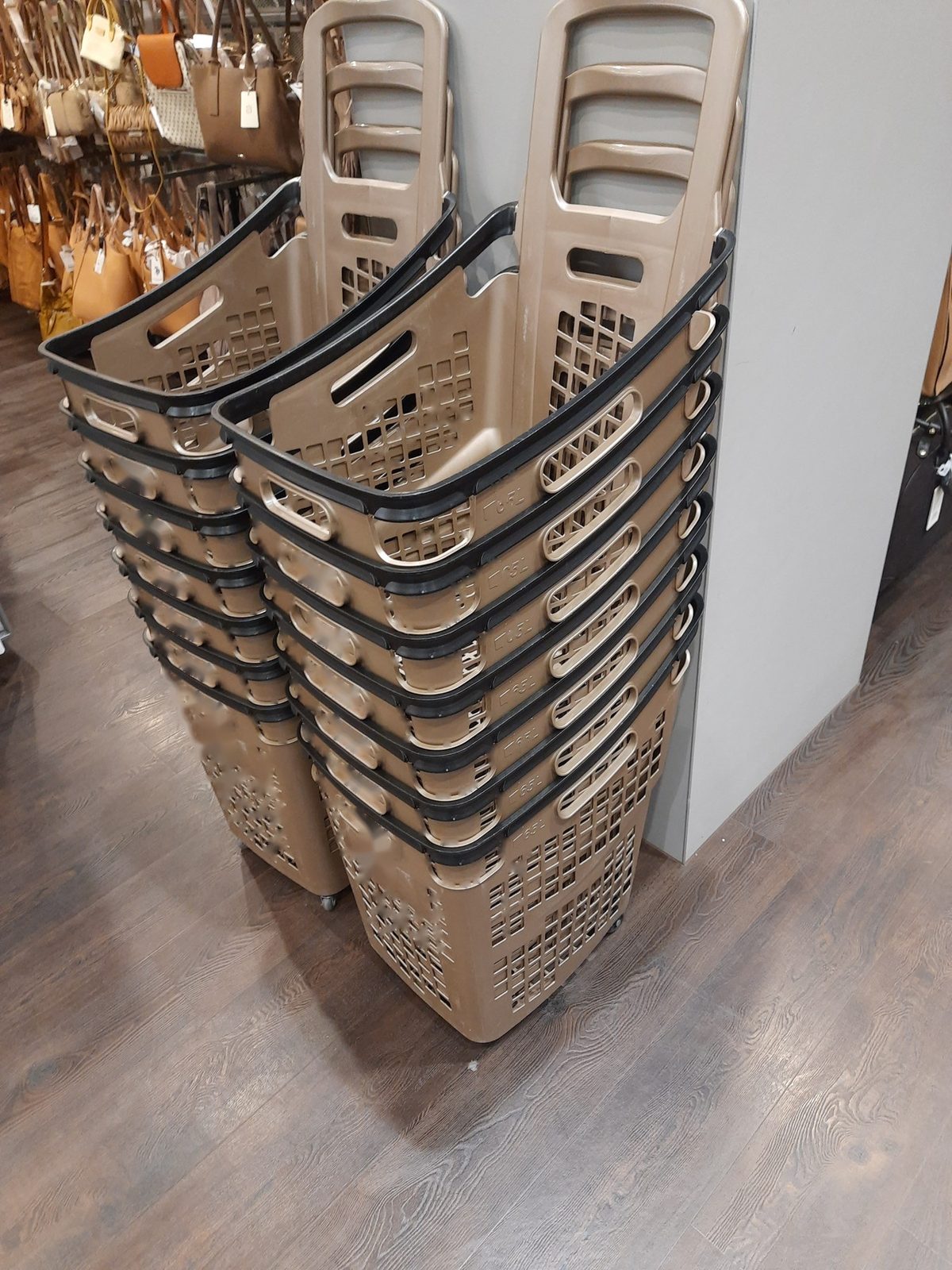 Two stacks of plastic wheeled baskets with long handles
