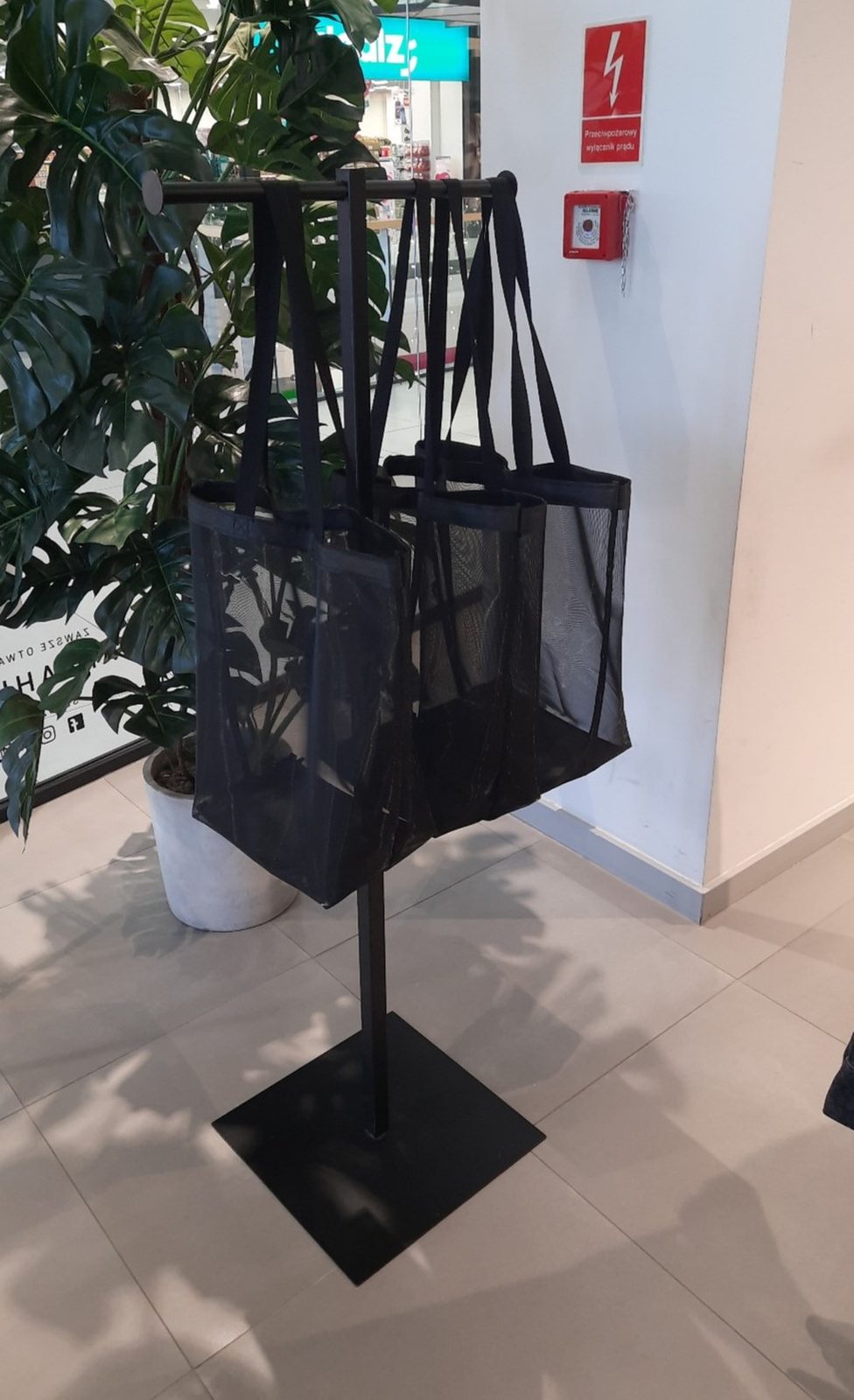 A stand with mesh shopping bags at a store entrance