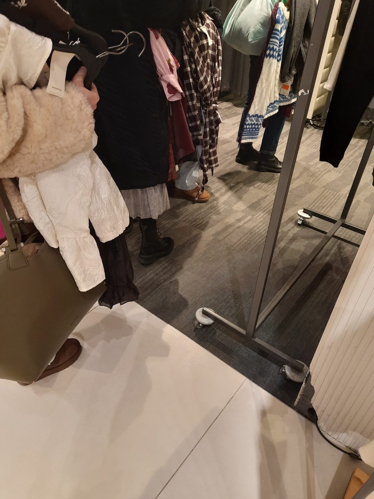 Customers with armfuls of clothes queuing for the fitting room
