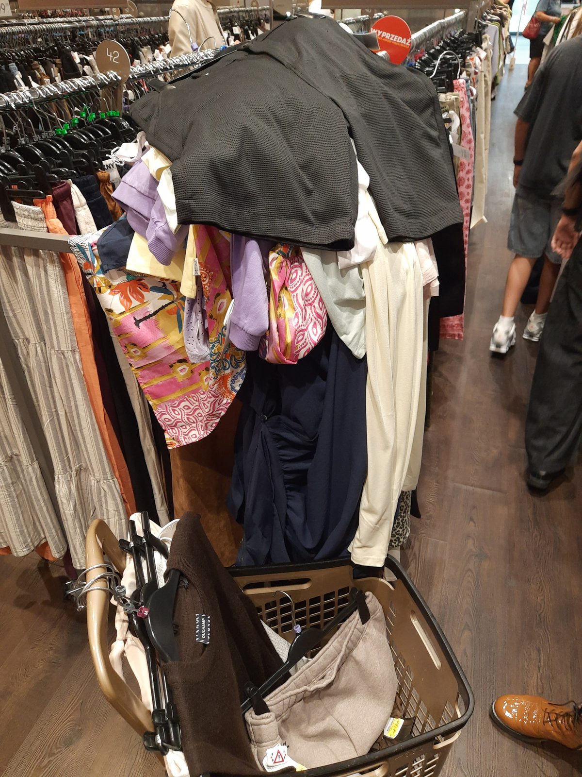 Clothes piled on a rack above an overloaded shopping basket